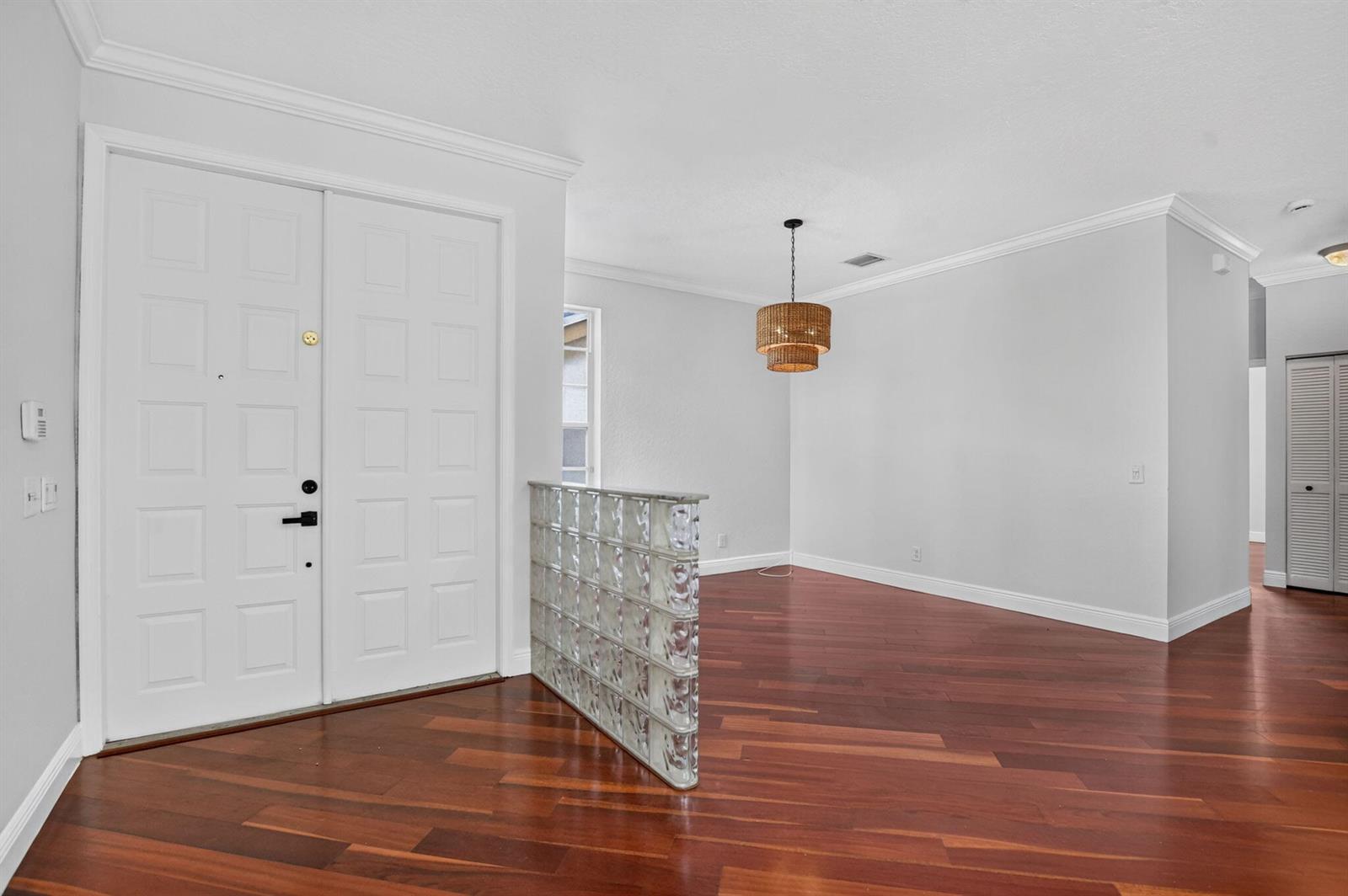 An entryway with hardwood floors, a glass block partition, and a hanging woven light fixture — 18044 Jazz Lane, Boca Raton FL 33496, BOCA RATON, FL