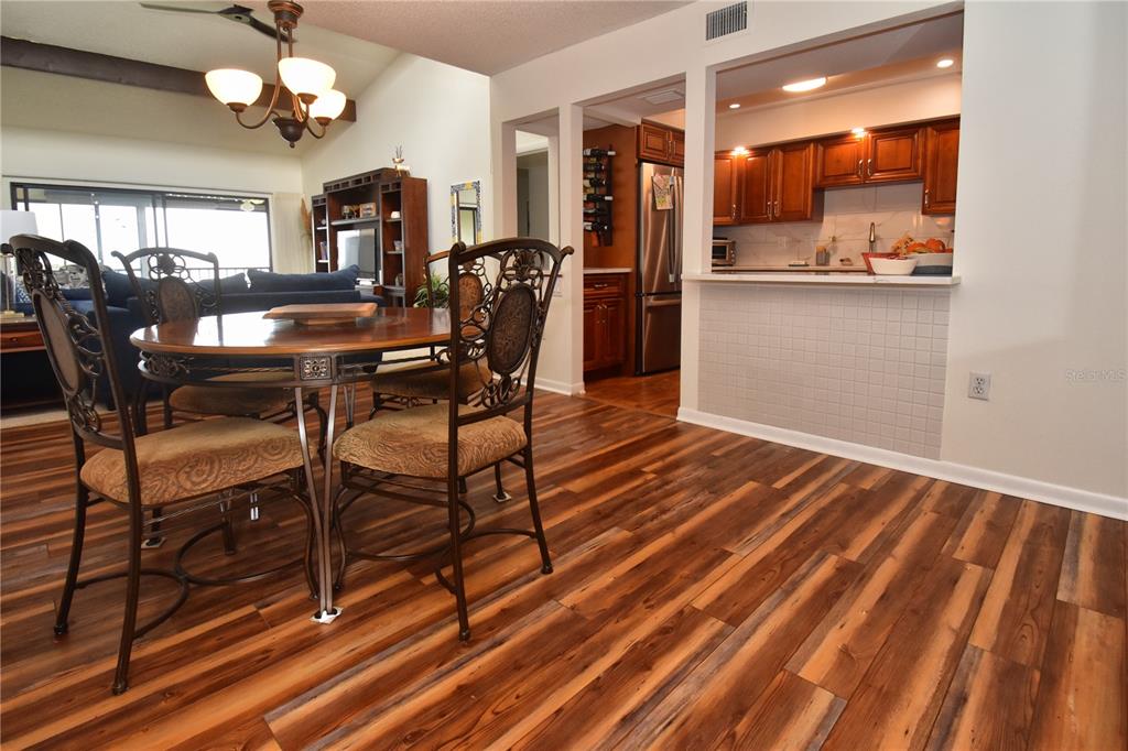 A dining area with a wooden table and chairs sits next to a kitchen pass-through — 1503 CLOWER CREEK DRIVE UNIT HA262, SARASOTA, FL