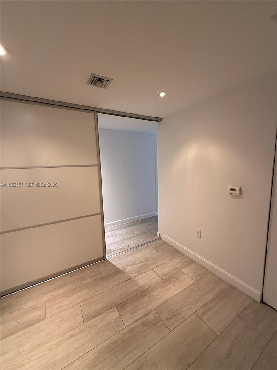 A room with light wood-look tile flooring and a sliding door leading to a hallway — 45 SW 9th St # 1004, Miami FL 33130, MIAMI, FL