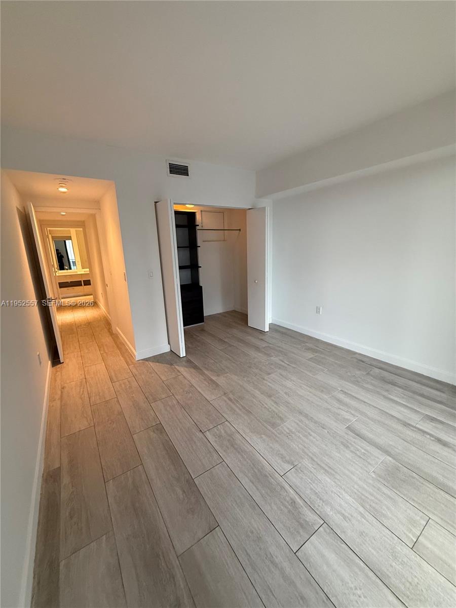 An empty room features light wood-look tile flooring, white walls, and an open closet — 45 SW 9th St # 1004, Miami FL 33130, MIAMI, FL