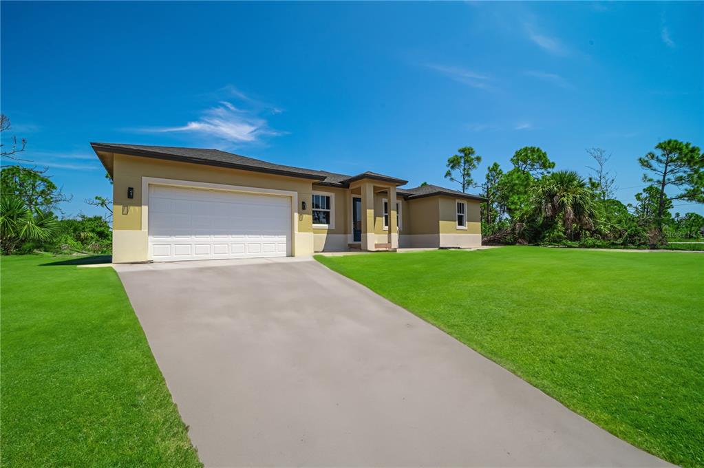 A single-story house with a two-car garage and a concrete driveway under a blue sky — xx 15101 BRAINBRIDGE CIRCLE, PORT CHARLOTTE, FL