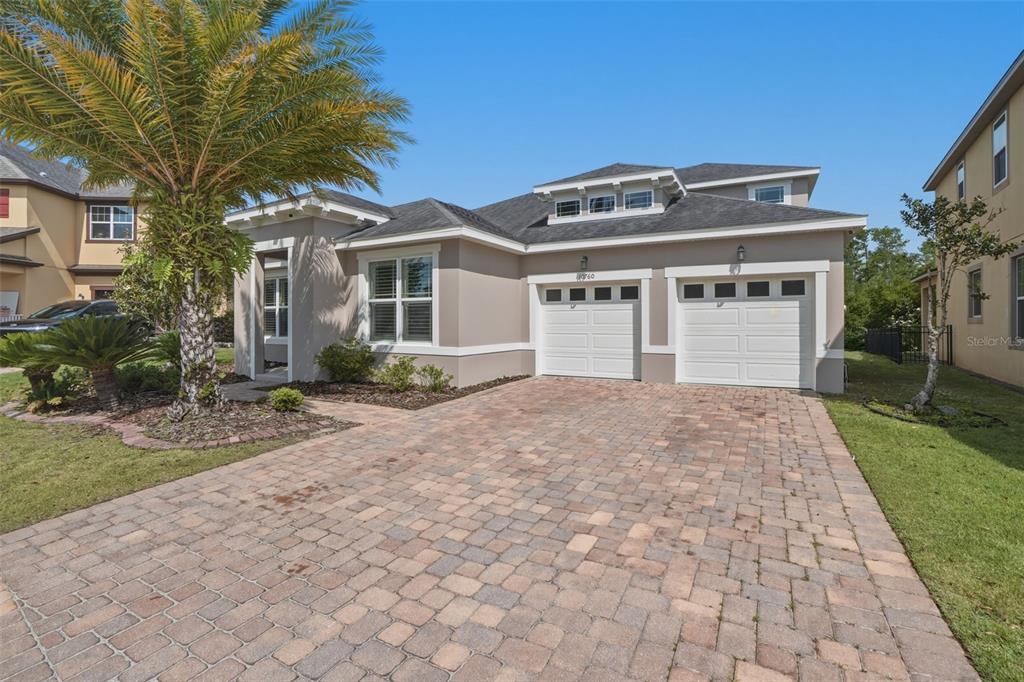 A single-story house with a paver driveway, two-car garage, and a large palm tree — 10760 TIBBETT STREET, ORLANDO, FL