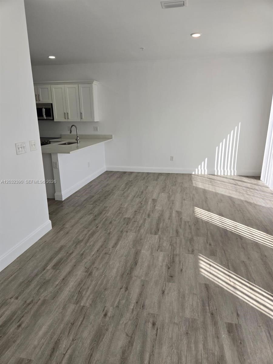 A kitchen with white cabinets and a breakfast bar opens into a living area — 4217 Gulfstream Rd, Lake Worth FL 33461, LAKE WORTH, FL