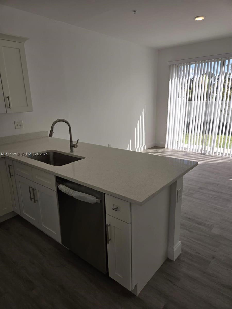 A kitchen island with a stainless steel sink and dishwasher sits on light wood flooring — 4217 Gulfstream Rd, Lake Worth FL 33461, LAKE WORTH, FL