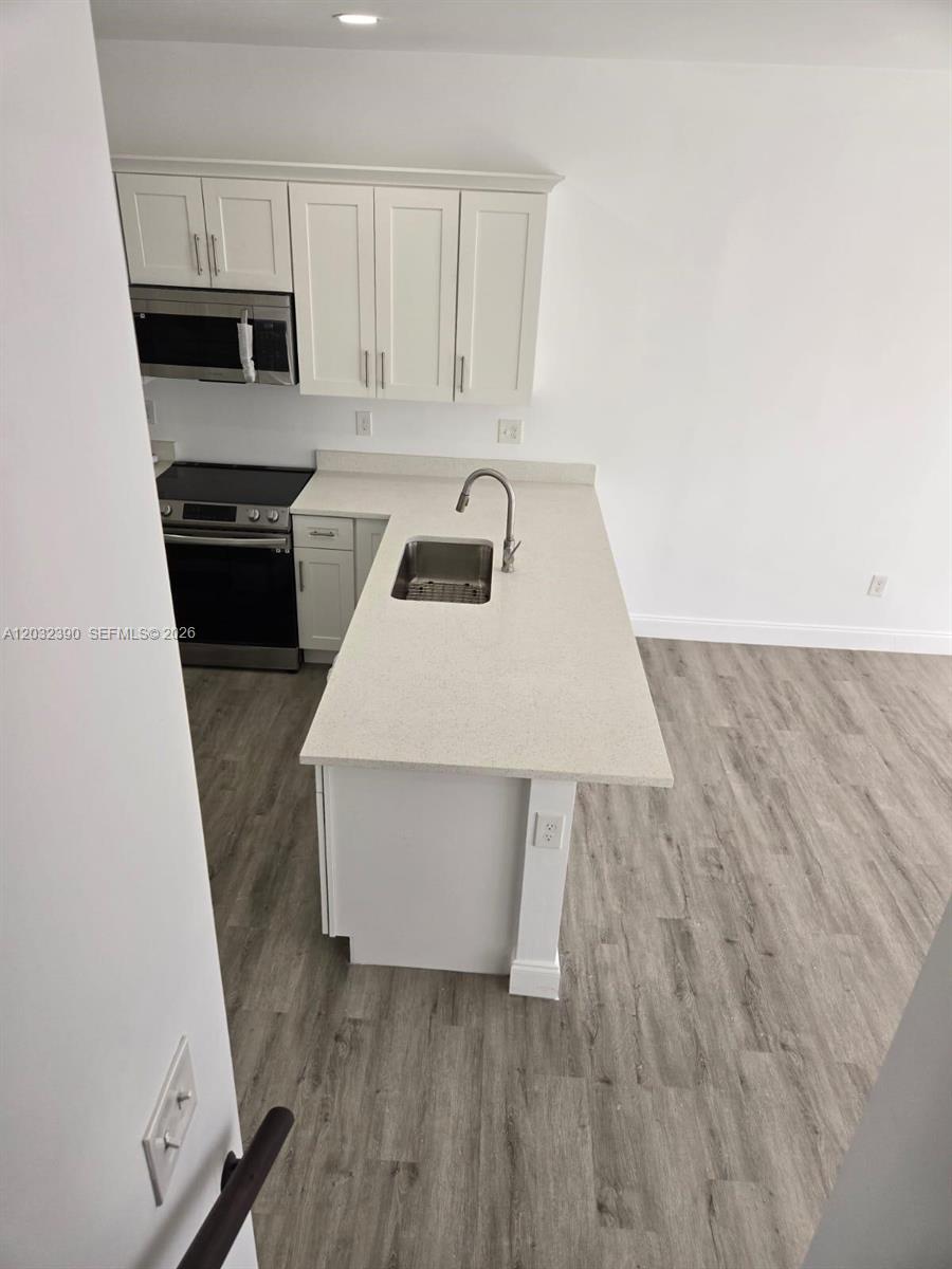 A modern kitchen features white cabinets, stainless steel appliances, and a quartz-topped island — 4217 Gulfstream Rd, Lake Worth FL 33461, LAKE WORTH, FL