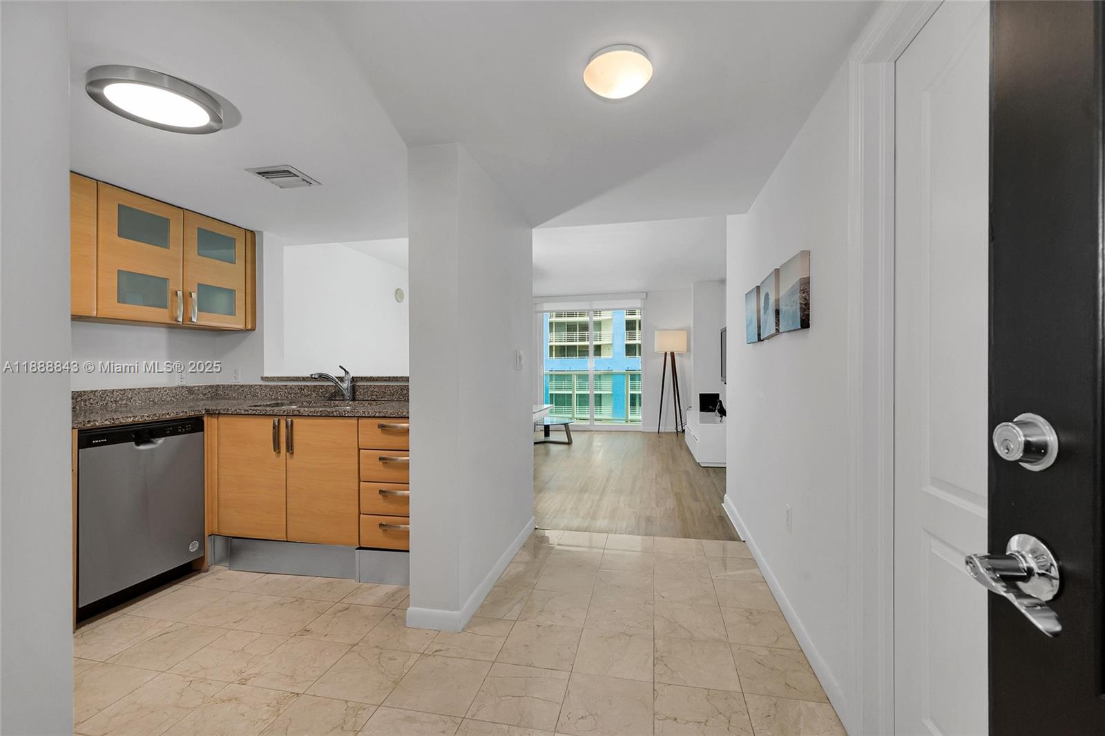 A kitchen with light wood cabinets and a tiled floor opens into a living area — 2101 BRICKELL AVENUE # 905, Miami FL 33129, MIAMI, FL