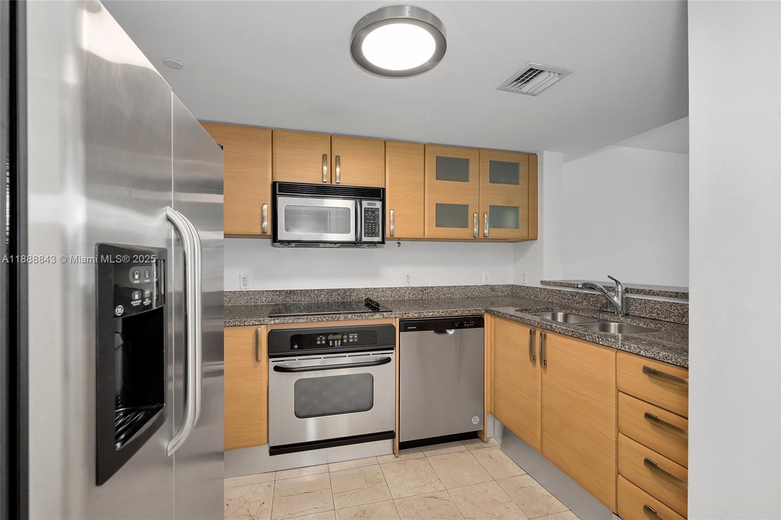 This kitchen features light wood cabinets, stainless steel appliances, and speckled granite countertops — 2101 BRICKELL AVENUE # 905, Miami FL 33129, MIAMI, FL