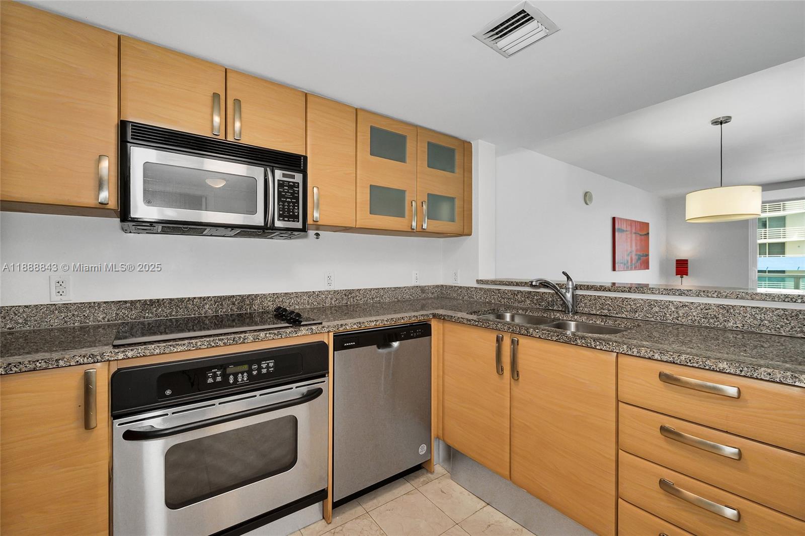 A kitchen features light wood cabinets, granite countertops, and stainless steel appliances — 2101 BRICKELL AVENUE # 905, Miami FL 33129, MIAMI, FL