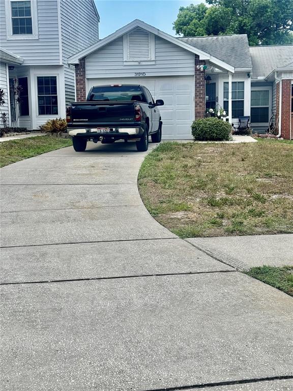 A black pickup truck is parked in the driveway of a light-colored suburban house — 3121 BEECHER DRIVE E UNIT D, PALM HARBOR, FL
