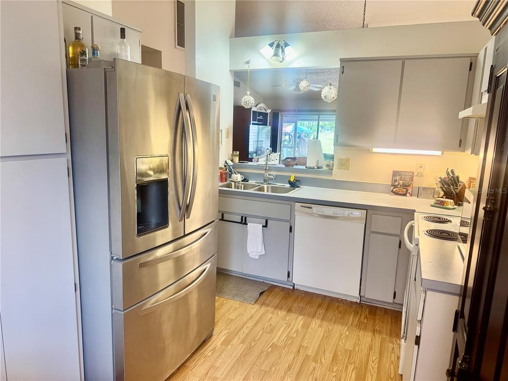A kitchen features stainless steel appliances, gray cabinets, and light wood-look flooring — 3121 BEECHER DRIVE E UNIT D, PALM HARBOR, FL