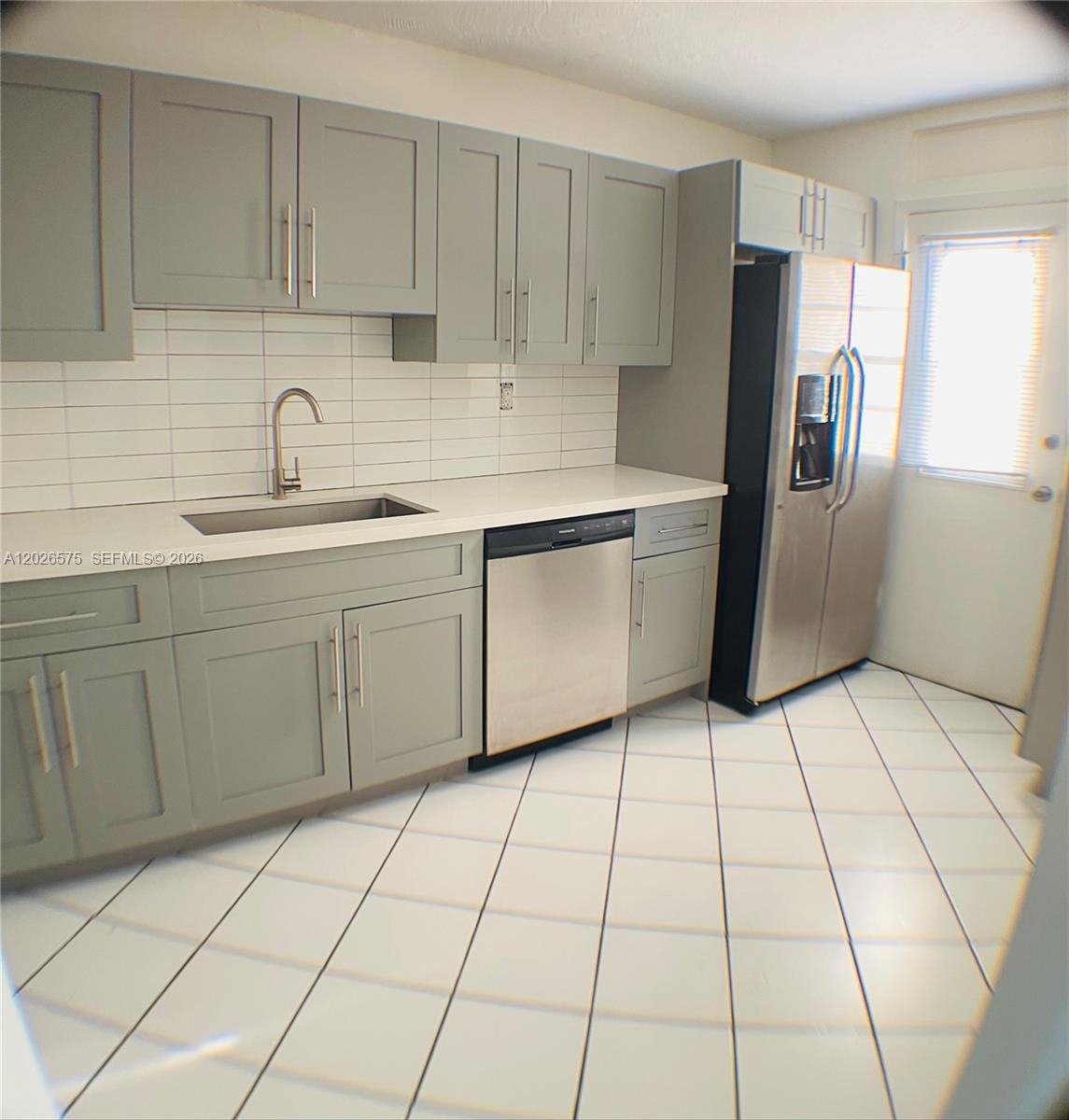 A kitchen features gray shaker cabinets, white countertops, stainless steel appliances, and white tiled flooring — 12590 NE 16th Ave # 610, North Miami FL 33161, NORTH MIAMI, FL