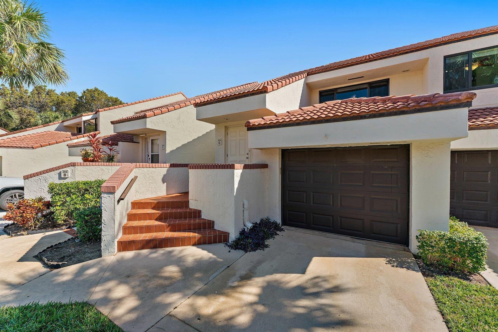 An exterior view of a multi-unit residential building with a garage and tiled steps — 204 Sea Oats Drive # G, Juno Beach FL 33408, JUNO BEACH, FL