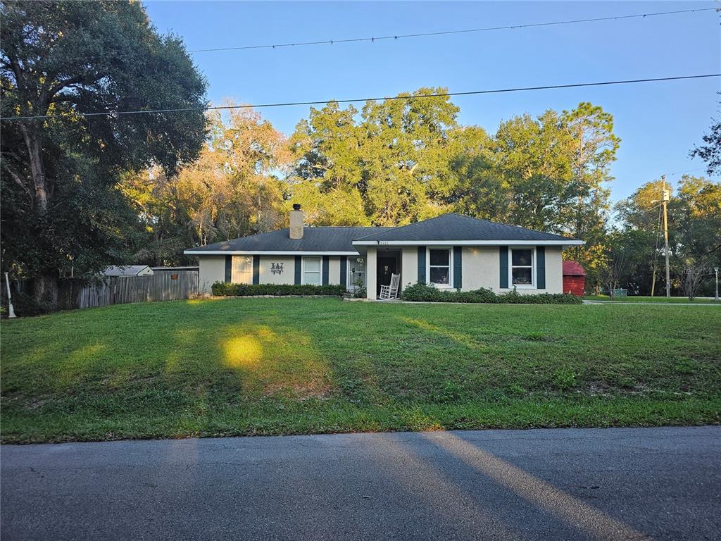 A single-story ranch-style house with a light-colored exterior sits behind a large, grassy front lawn — 5925 SE 165TH COURT, OCKLAWAHA, FL