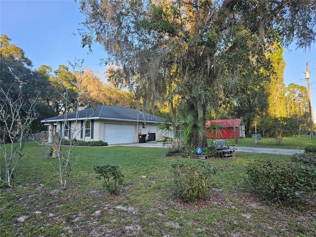 A single-story house with a white garage and a red shed under large oak trees — 5925 SE 165TH COURT, OCKLAWAHA, FL