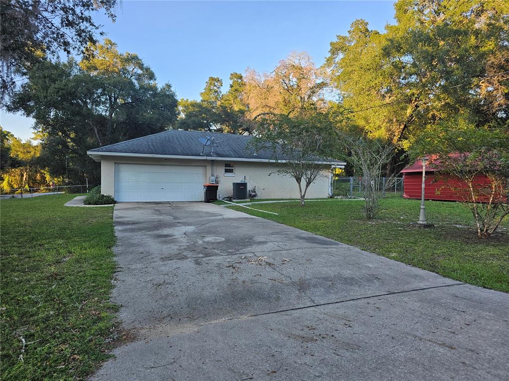 A concrete driveway leads to the attached garage of a single-story house with a yard — 5925 SE 165TH COURT, OCKLAWAHA, FL