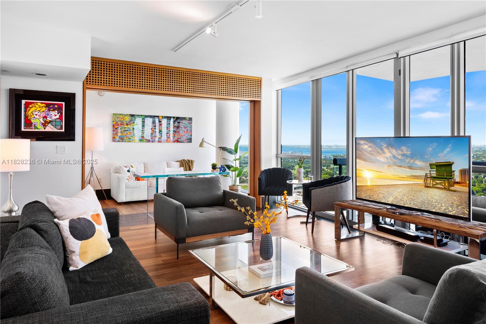 A modern living room features floor-to-ceiling windows, hardwood floors, and a view of the ocean — 101 20th St # 3803, Miami Beach FL 33139, MIAMI BEACH, FL