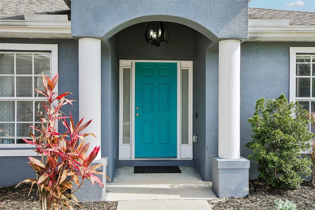 A turquoise front door is centered between two white columns under a covered entryway — 4628 ADDERTON AVENUE, NORTH PORT, FL