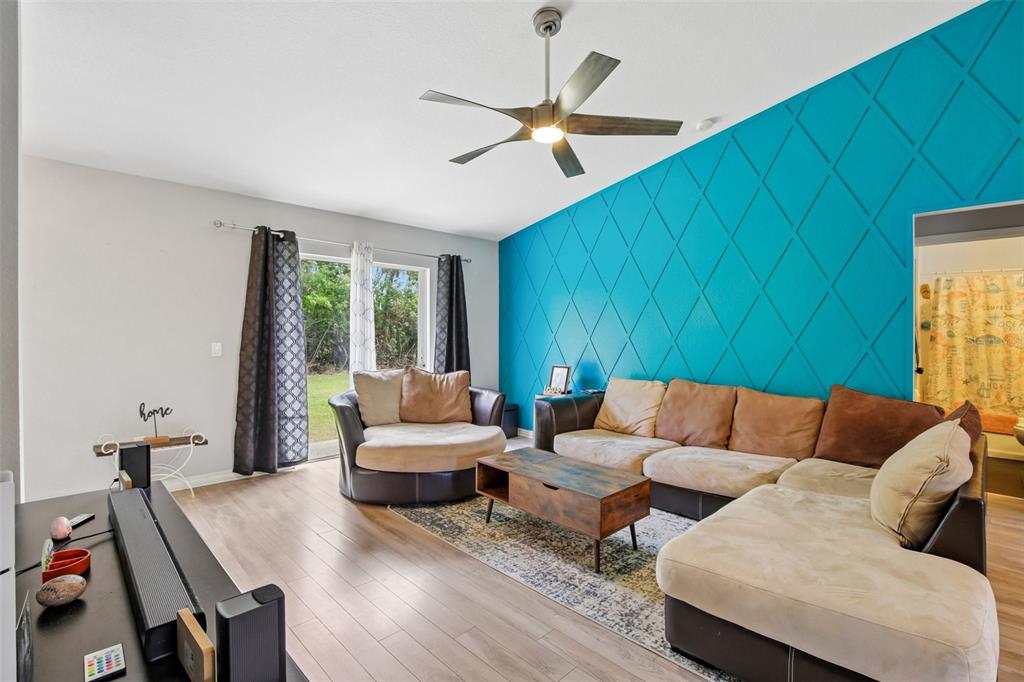 A living room features a bright blue accent wall with diamond molding and a sectional sofa — 4628 ADDERTON AVENUE, NORTH PORT, FL