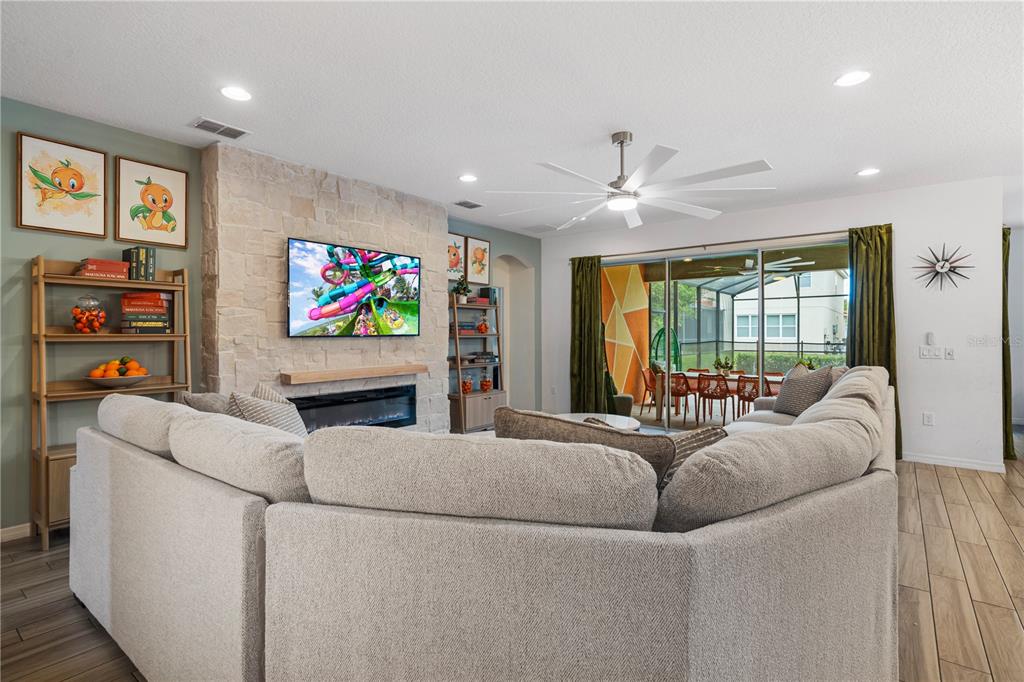 A living room features a stone fireplace, a large sectional sofa, and sliding glass doors — 7009 OAKWOOD STREET, DAVENPORT, FL