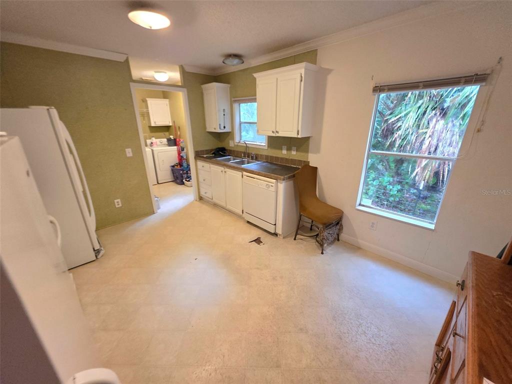 A kitchen features white cabinets, a window, and a laundry area visible in the background — 14263 ANNUTALAGA AVENUE, BROOKSVILLE, FL