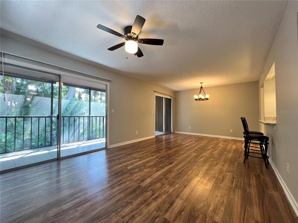 An open living and dining area features wood-look flooring, a ceiling fan, and sliding glass doors — 100 SWEETGUM WOODS COURT UNIT 3D, DELTONA, FL