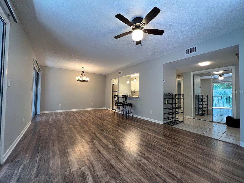 A living and dining area with wood-look flooring, a ceiling fan, and a kitchen pass-through — 100 SWEETGUM WOODS COURT UNIT 3D, DELTONA, FL