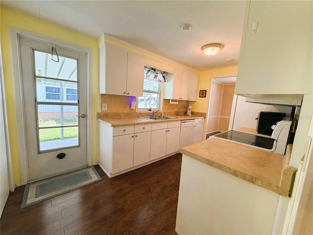 A kitchen with white cabinets, laminate countertops, wood-look flooring, and a glass-paneled exterior door — 139 ASPEN CIRCLE, LEESBURG, FL