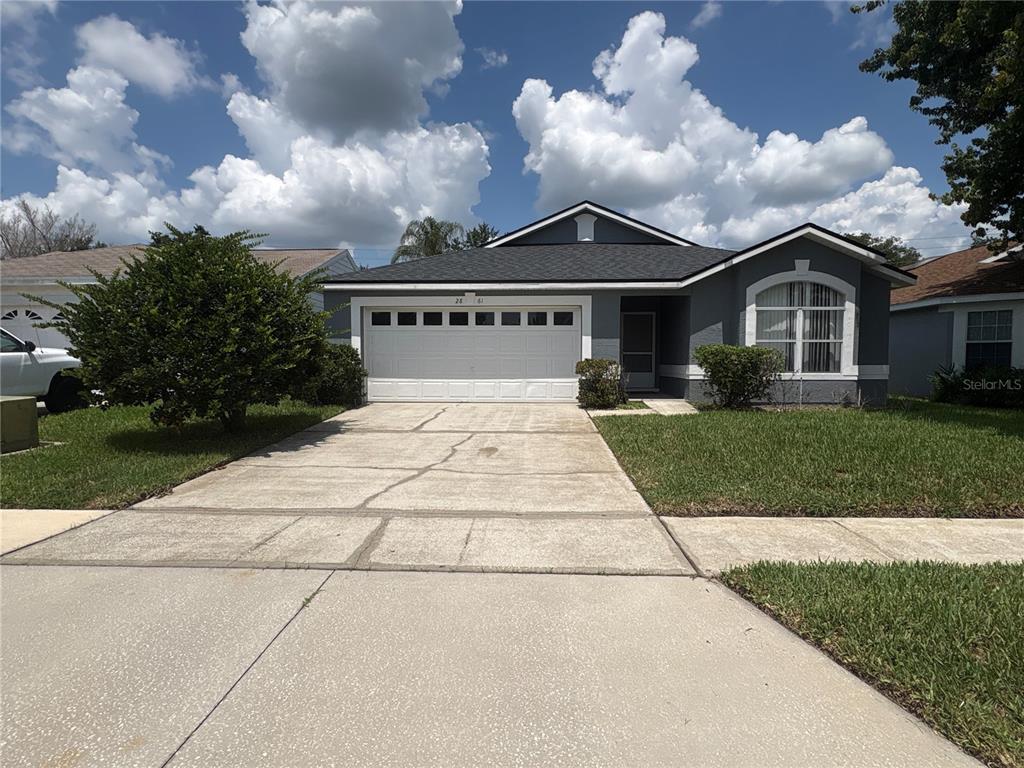 A gray single-story house features a white garage door, a concrete driveway, and a lawn — 2861 FALLING TREE CIRCLE, ORLANDO, FL