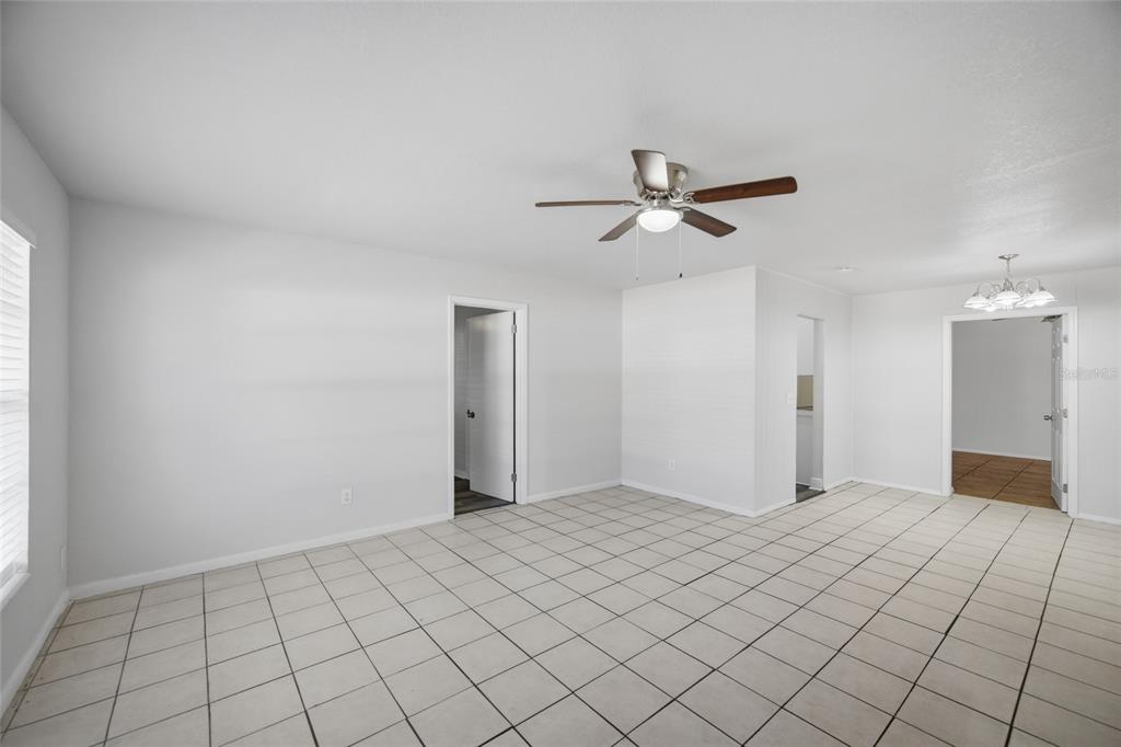 A room with white walls, a tiled floor, a ceiling fan, and multiple doorways — 7102 DELLWOOD DRIVE, TAMPA, FL