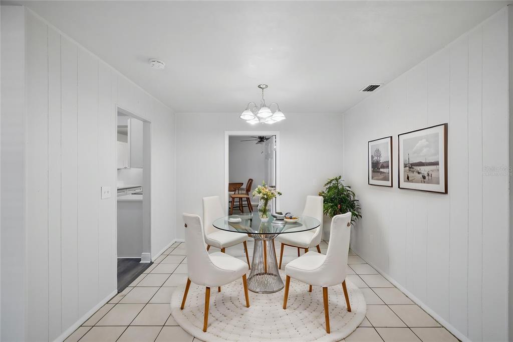 A dining room features a glass-topped table, four white chairs, and white paneled walls — 7102 DELLWOOD DRIVE, TAMPA, FL