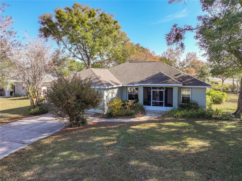 A single-story house with a screened-in porch and a concrete driveway sits on a lawn — 3061 NW 49TH AVENUE, OCALA, FL
