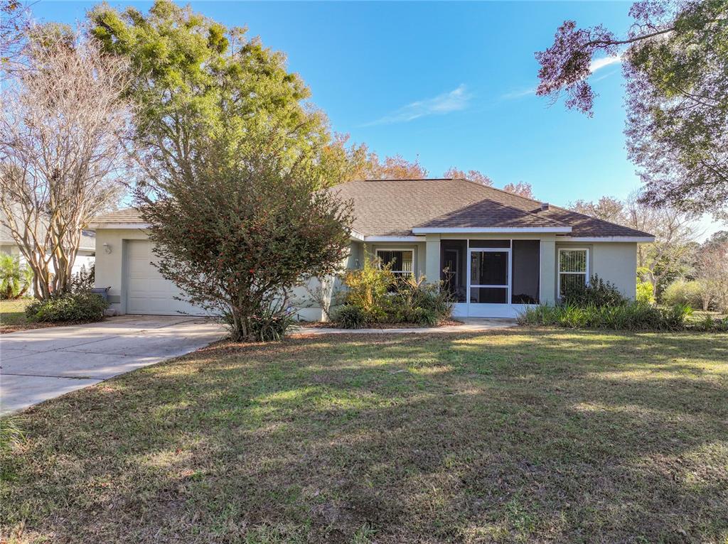 A single-story house with a beige exterior, a two-car garage, and a screened front porch — 3061 NW 49TH AVENUE, OCALA, FL