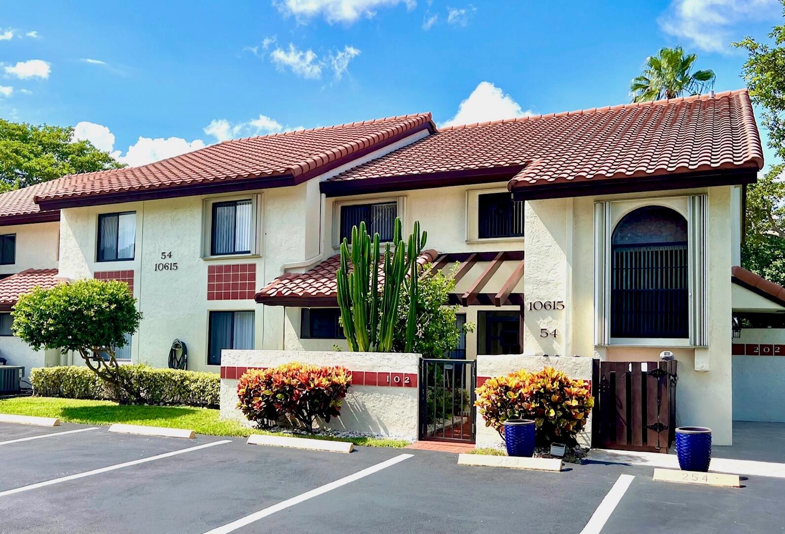 A two-story stucco apartment building features a red tile roof and a small gated courtyard — 10615 Ocean Palm Way # 102, Boynton Beach FL 33437, BOYNTON BEACH, FL