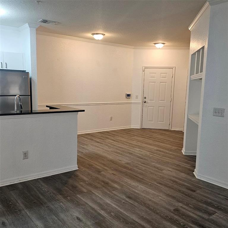 An open-concept living area features wood-look flooring, white walls with chair rail molding, and a kitchen — 3599 CONROY ROAD UNIT 934, ORLANDO, FL