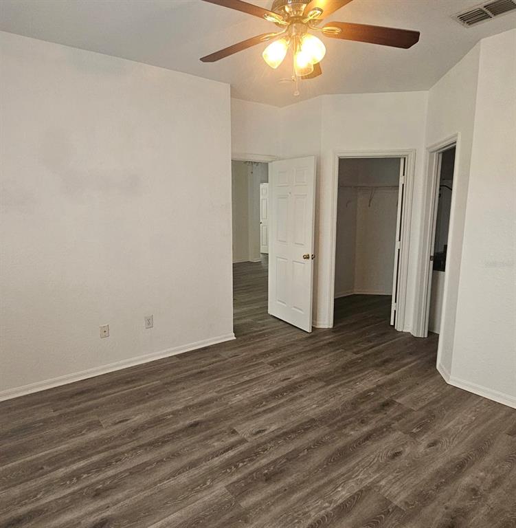 An empty room features white walls, gray wood-look flooring, a ceiling fan, and open doorways — 3599 CONROY ROAD UNIT 934, ORLANDO, FL