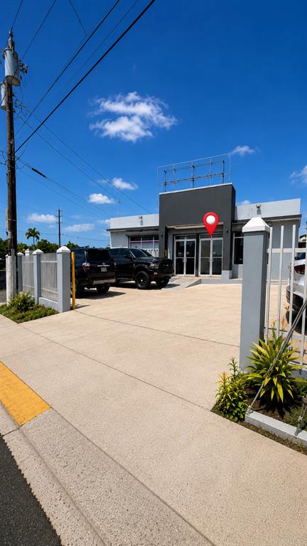 A modern one-story commercial building with a paved parking lot and two black trucks — 3 MARGINAL, CAROLINA, PR