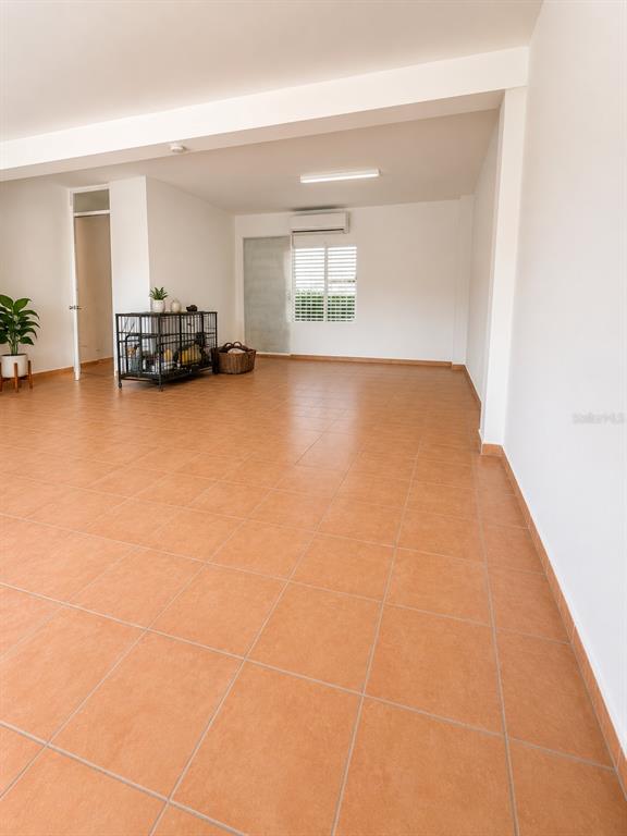 An open-plan room features terracotta tile flooring, white walls, and a metal storage crate — 3 MARGINAL, CAROLINA, PR