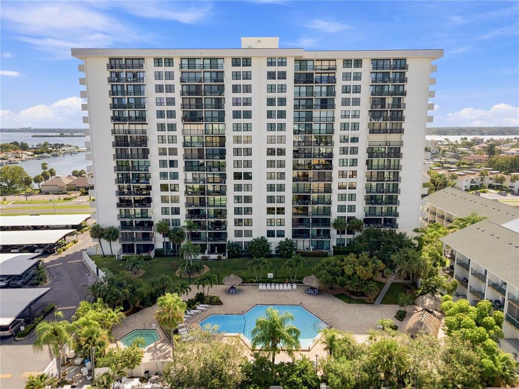 An aerial view shows a tall residential building with balconies overlooking a swimming pool area — 400 ISLAND WAY UNIT 411, CLEARWATER, FL
