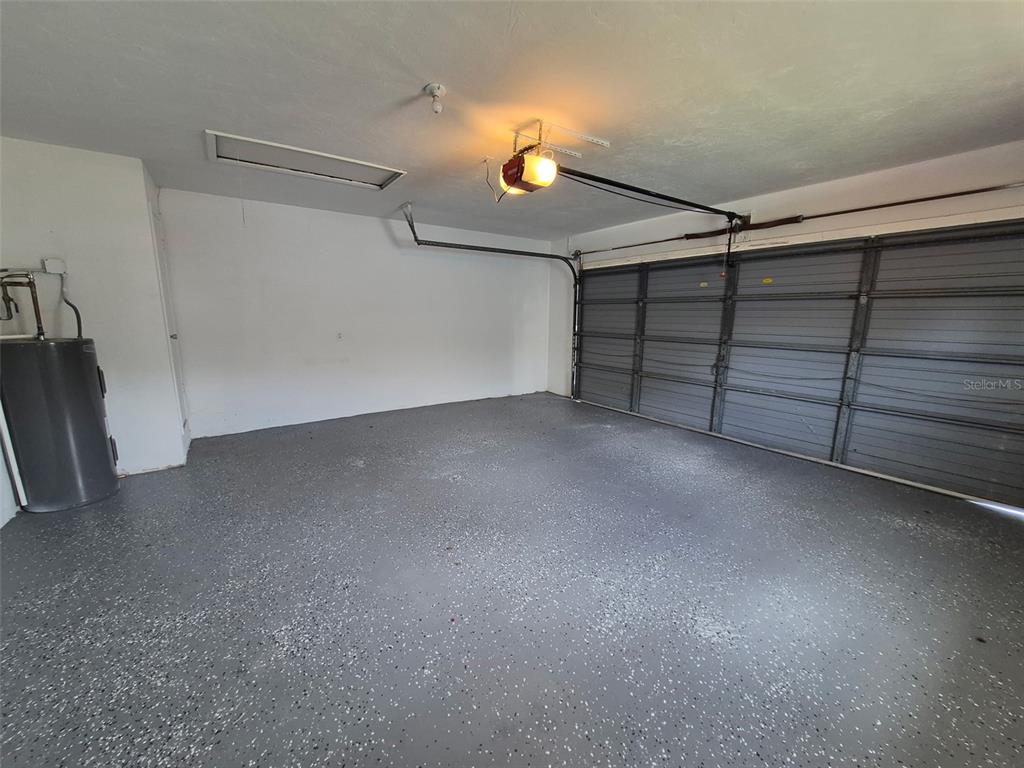 A garage with a gray speckled epoxy floor, a water heater, and a sectional door — 229 W CASURINA PLACE, BEVERLY HILLS, FL