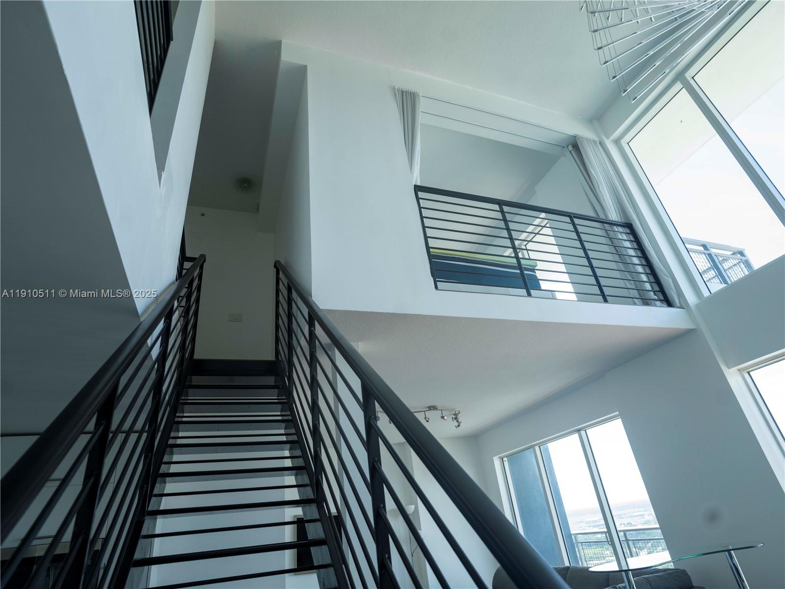 A modern staircase with black metal railings leads to an upper loft area — 60 SW 13th St # 4805, Miami FL 33130, MIAMI, FL