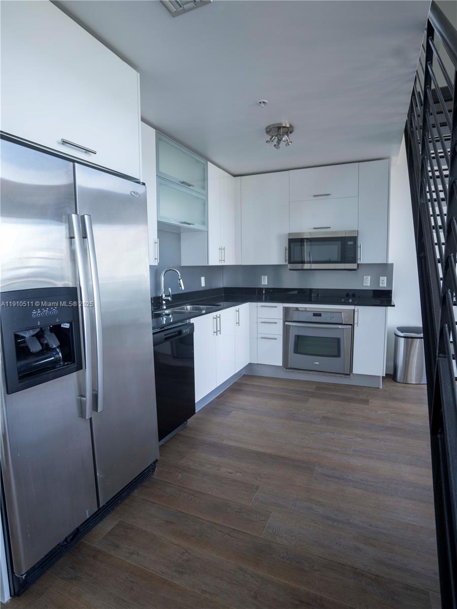 A modern kitchen features white cabinets, stainless steel appliances, and dark countertops — 60 SW 13th St # 4805, Miami FL 33130, MIAMI, FL