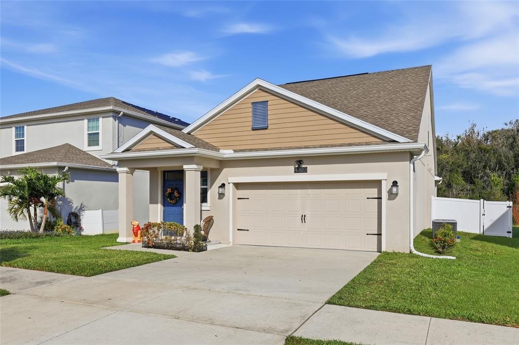 A single-story house with a beige stucco exterior, tan siding, and a two-car garage — 4303 SEVEN CANYONS DRIVE, KISSIMMEE, FL