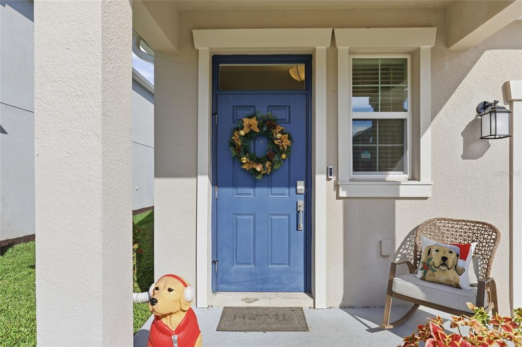 A blue front door with a wreath sits on a porch with a rocking chair — 4303 SEVEN CANYONS DRIVE, KISSIMMEE, FL