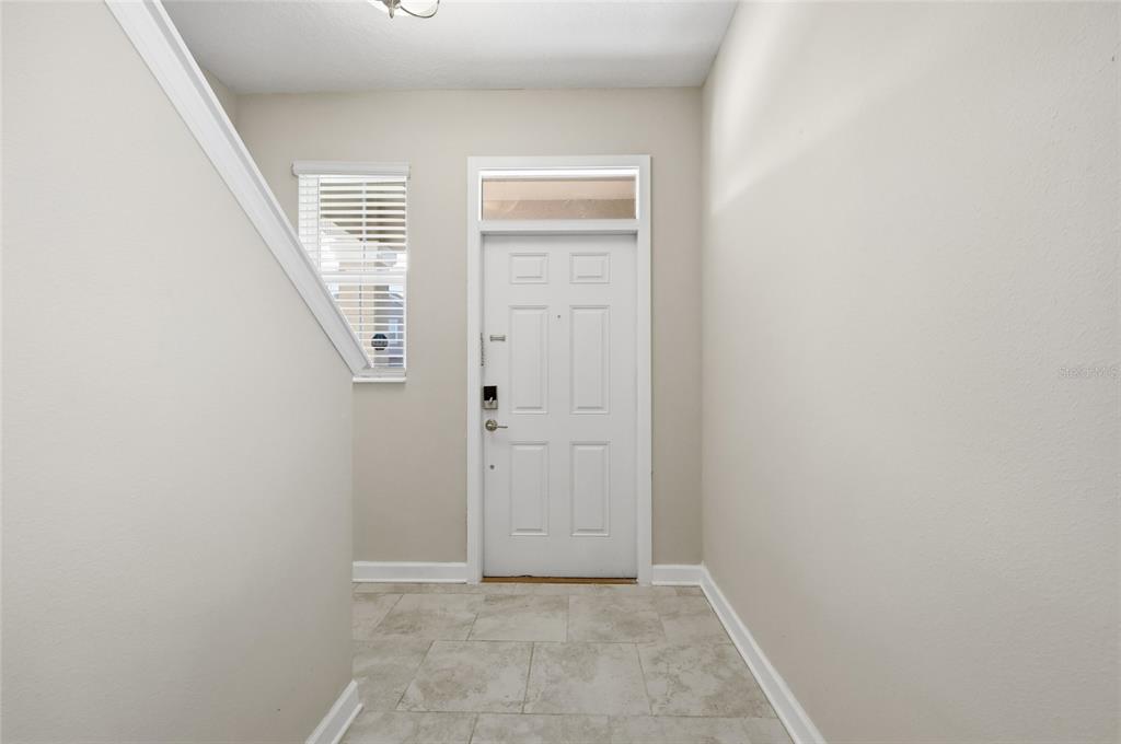 An entryway features a white front door, a side window with blinds, and tiled flooring — 4303 SEVEN CANYONS DRIVE, KISSIMMEE, FL