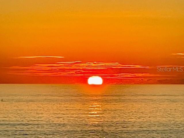 A vibrant orange sunset glows over the horizon above a calm body of water — 5757 GULF OF MEXICO DRIVE UNIT 202, LONGBOAT KEY, FL