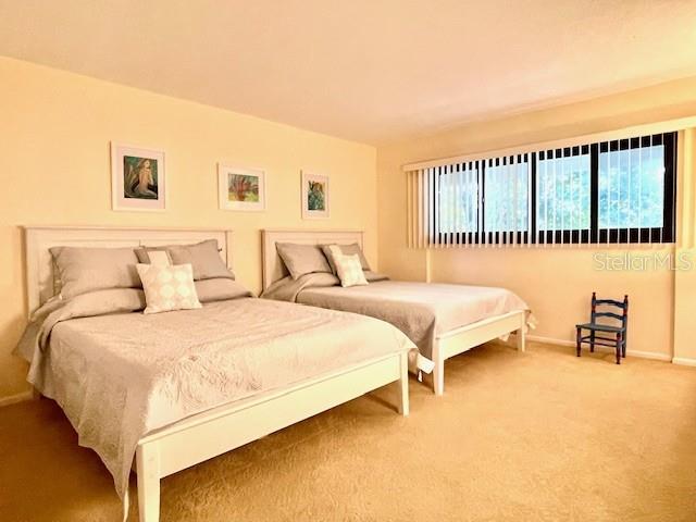 A bedroom features two beds with light-colored bedding, framed wall art, and a large window — 5757 GULF OF MEXICO DRIVE UNIT 202, LONGBOAT KEY, FL
