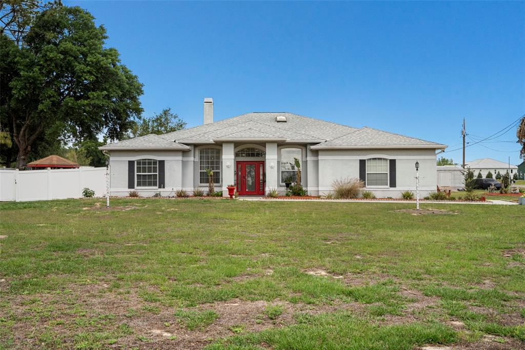 A single-story house with a grey exterior, a red front door, and a large lawn — 6702 JOSIE DRIVE, SEFFNER, FL
