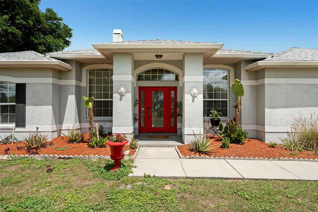 A single-story house with a red front door, two lion head wall ornaments, and landscaping — 6702 JOSIE DRIVE, SEFFNER, FL