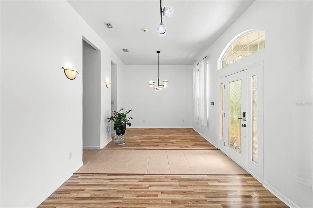 An entryway with wood-look flooring, a tiled transition area, and a modern chandelier — 6702 JOSIE DRIVE, SEFFNER, FL
