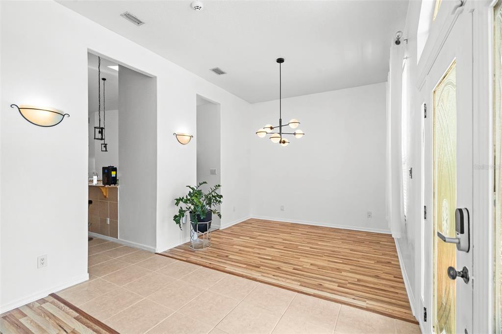A dining area features wood flooring, a modern chandelier, and an adjacent tiled entryway — 6702 JOSIE DRIVE, SEFFNER, FL